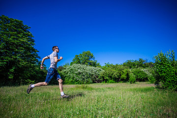 A young man runs along the green grass