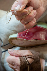 Obraz na płótnie Canvas The shoemaker repairs a shoe at his work bench
