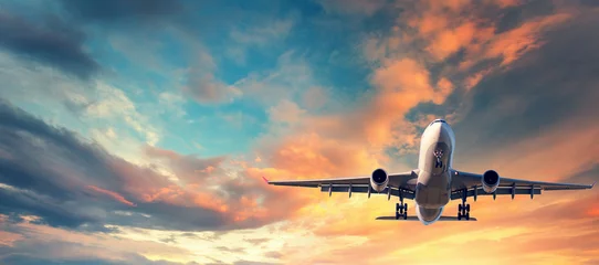 Foto op Plexiglas Vliegtuig Landend vliegtuig. Landschap met wit passagiersvliegtuig vliegt in de blauwe lucht met veelkleurige wolken bij zonsondergang. Reizen achtergrond. Passagiersvliegtuig. Zakenreis. Commerciële vliegtuigen