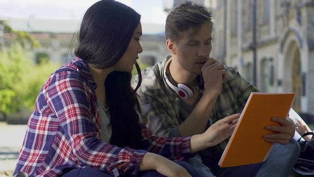 Couple of students carefully reading topics of thesis works, higher education
