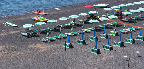 Calabria, Italia: una delle spiagge nere di San Nicola Arcella, con ombrelloni e sedie a sdraio...