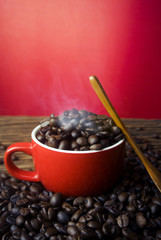 Fototapeta na wymiar red cup with spoon and coffee beans hot on wood table background