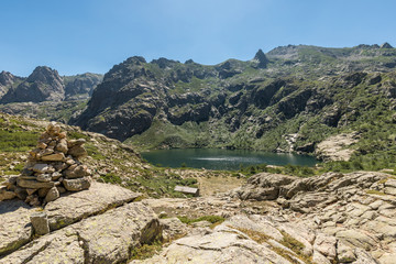 Fototapeta na wymiar Stone cairn overlooking Lac de Melo in mountains of Corsica