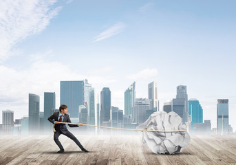 Man pulling with effort big crumpled ball of paper as creativity sign