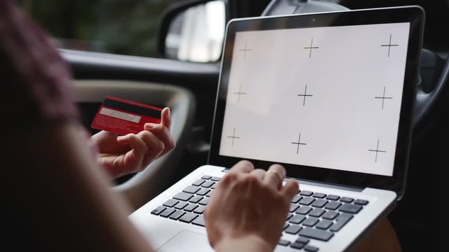 Anonymous woman pays for credit card purchases over the Internet with the laptop sitting in the car.