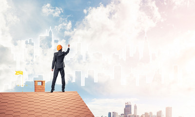 Man architect draw silhouette of modern city on blue sky. Mixed 