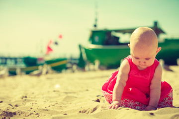 Little baby sitting and playing on beach