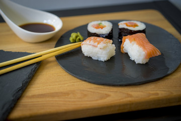 Sushi on a wooden table on black slate plate with soy sauce and chopsticks