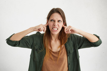 Agressive female plugging her ears being angry with her neighbours who are very noisy. Irritated...