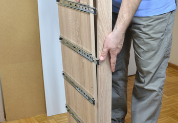 Man assembling parts of a new piece of furniture with drawer slides