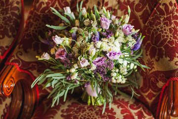Fototapeta na wymiar Beautiful purple wedding bouquet in bride's hands
