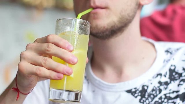 A young guy drinking lemonade in a cafe on the street