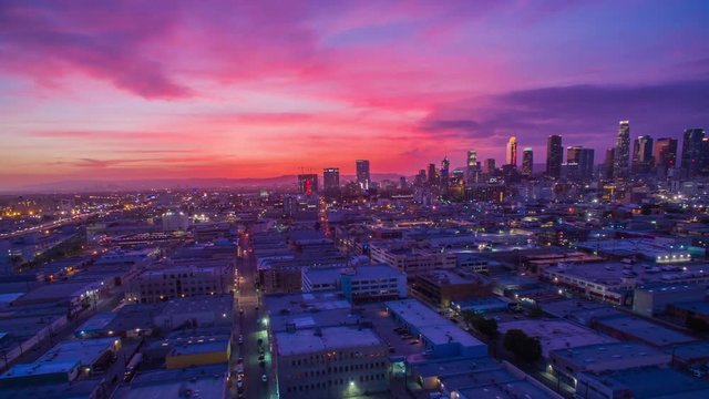 Aerial timelapse in motion (hyperlapse) at sunset facing downtown Los Angeles at twilight with the sky changing from day to night with stunning fiery pink and blue skies and high-rise building lights