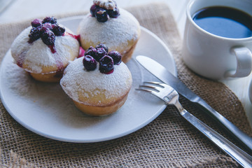cupcakes with berries on white wooden background