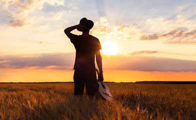 Person in warm summer fields with guitar, musician - Powered by Adobe