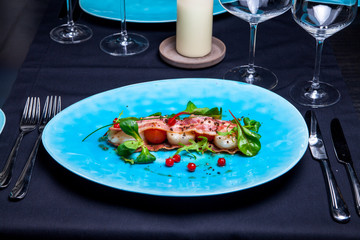 Salad with sea scallops, basil, bacon and cranberries on blue plate served in restaurant 