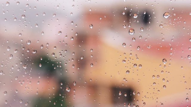 Window With Raindrops On It And Blurred Town Behind 