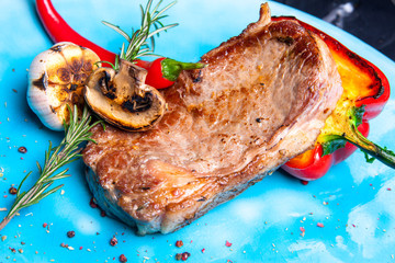 Veal steak with grilled vegetables: mushrooms and peppers on the grill, rosemary and chili