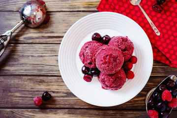 Summer cold refreshing dessert, ice cream, berry sorbet in balls with cherry and raspberries on a dark wooden background - obrazy, fototapety, plakaty