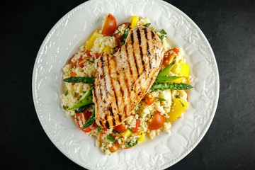 couscous salad with grilled chicken and asparagus on white plate. stone table. healthy food