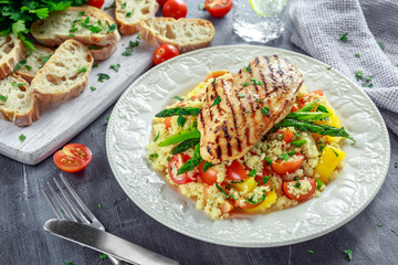 couscous salad with grilled chicken and asparagus on white plate. healthy food