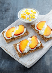 Homemade Crispbread toast with Cottage Cheese and nectarine on white wooden board.