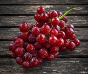 Ripe red grape. Pink bunch in a old rustic wooden table