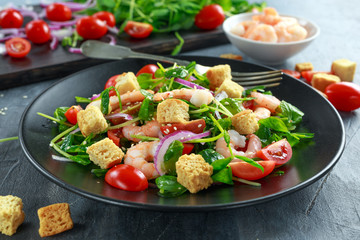 Fresh Healthy Prawns salad with tomatoes, red onion on black plate. concept healthy food