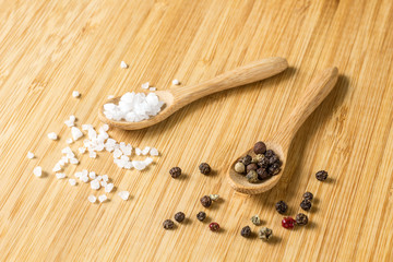 salt and pepper on wooden spoons on wooden table