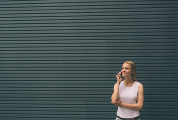 beautiful young blonde in the street. Female hipster on a gray background using a mobile phone. lifestyle