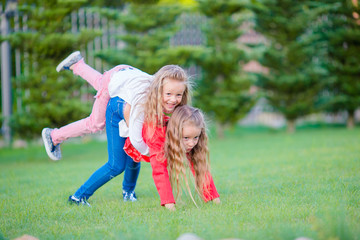 Fototapeta premium Little happy girls are having fun around on a green lawn