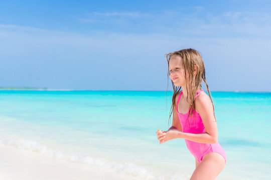 Happy adorable little girl walking on the white beach