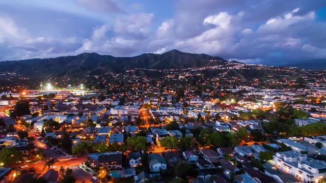 Aerial timelapse in motion or hyperlapse in Los Angeles at twilight with lightning storm and clouds forming changing from day to night. Mountains and LA city traffic below.