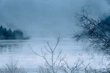 Rain and mist on ice covered northern lake in winter