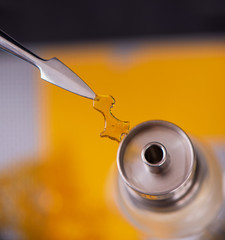 Fototapeta premium Dabbing tool with small piece of cannabis oil aka shatter - medical marijuana concentrates concept