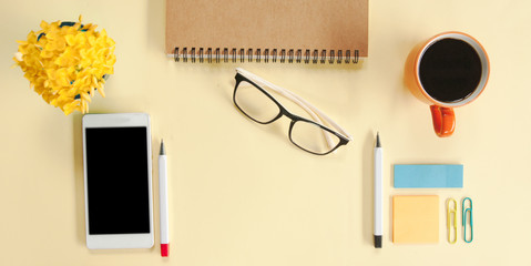 Female desk office with notebook , coffee cup , smart phone, notepad, glasses, pen and flower on...