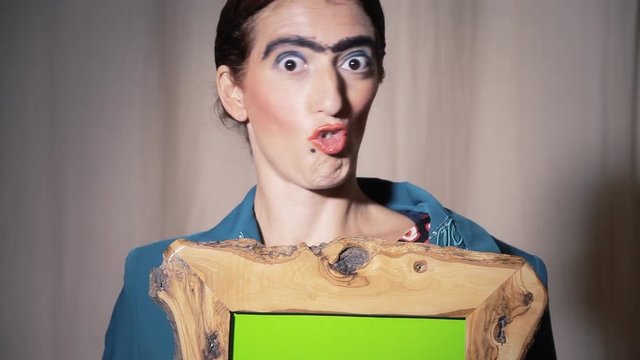 A funny ugly woman hides behind a wooden frame with a green interior (use chroma key for good laughs). She slowly releases the shape, showing her ugliness.
