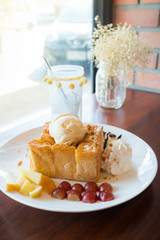 Honey toast with vanilla ice cream, whipped cream and chocolate syrup. Served with banana, grape and apple(selective focus)