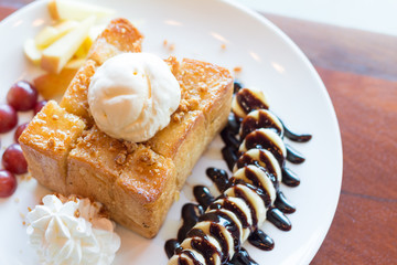 Honey toast with vanilla ice cream, whipped cream and chocolate syrup. Served with banana, grape and apple(selective focus)