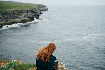 Beautiful young woman on a cliff of a mountain near the sea