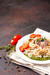Paste with tomatoes, seafood and spinach sauce in a plate on a table. Italian food. Selective focus. Copy space