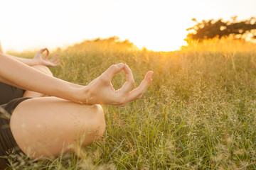 Close up of woman's hands meditating in a grass field. 