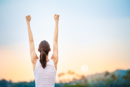 People winning achievement concept. Young woman with fist in the air celebrating success and happiness. 