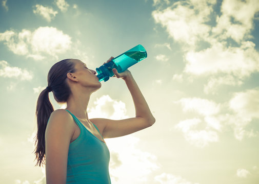 Woman drinking bottle of water outdoor on a hot summer day.