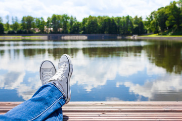 People relaxing in nature. Persons feet relaxing by a beautiful lake. 