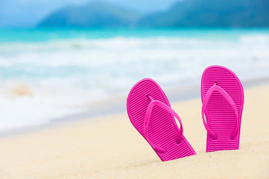 Beach holiday concept.  Pair of colorful sandals on the beach. 