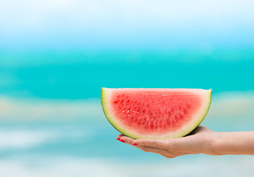 Hand Holding Slice Of Watermelon On The Beach. 