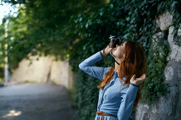 Beautiful young woman in a blue dress walking along the street with a camera