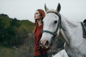 Beautiful young woman walking in the mountains with a horse