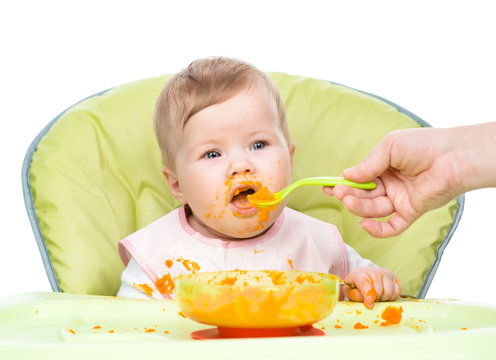 Mother feeding happy baby with a spoon